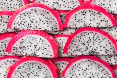 Tatlı ejderha meyvesi ya da pitaya dilimleri arka planda.