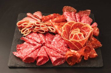 Tahtada farklı et parçaları var. Siyah bir arkaplanda.