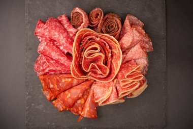 Tahtada farklı et parçaları var. Siyah bir arkaplanda.