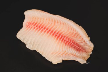 Siyah arkaplanda taze tilapia filetosu, üst görünüm. 