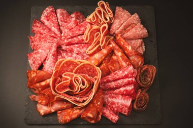 Tahtada farklı et parçaları var. Siyah bir arkaplanda.