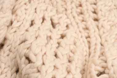 A fragment of beige knitted fabric, knitted from white sheep wool. Knitted background. 