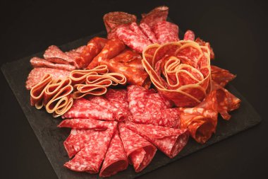 Tahtada farklı et parçaları var. Siyah bir arkaplanda.