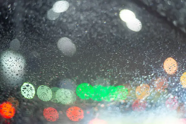 Yağmur damlaları ve ışıklarla bulanık arkaplan.