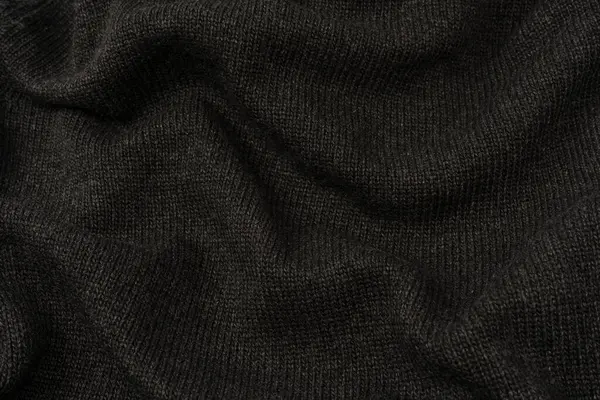 Arka plan olarak koyu gri süveter dokusu. Örgü desenli. Üst görünüm. 