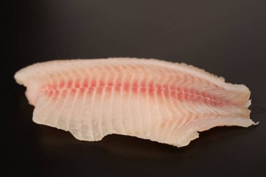 Siyah arkaplanda taze tilapia filetosu, üst görünüm. 