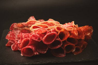 Tahtada farklı et parçaları var. Siyah bir arkaplanda.