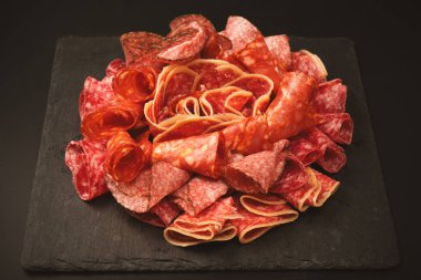 Tahtada farklı et parçaları var. Siyah bir arkaplanda.