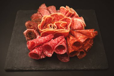 Tahtada farklı et parçaları var. Siyah bir arkaplanda.