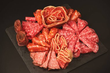 Tahtada farklı et parçaları var. Siyah bir arkaplanda.