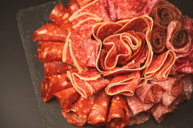 Tahtada farklı et parçaları var. Siyah bir arkaplanda.