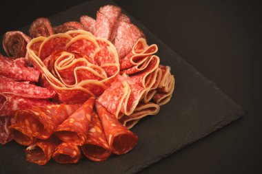 Tahtada farklı et parçaları var. Siyah bir arkaplanda.