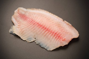 Siyah arkaplanda taze tilapia filetosu, üst görünüm. 