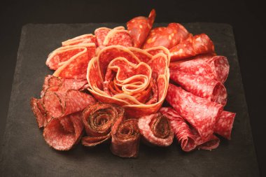 Tahtada farklı et parçaları var. Siyah bir arkaplanda.