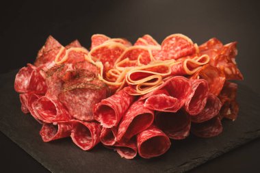 Tahtada farklı et parçaları var. Siyah bir arkaplanda.