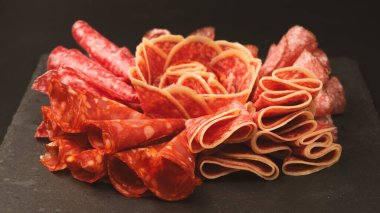 Tahtada farklı et parçaları var. Siyah bir arkaplanda.