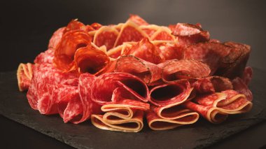 Tahtada farklı et parçaları var. Siyah bir arkaplanda.