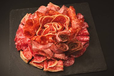 Tahtada farklı et parçaları var. Siyah bir arkaplanda.