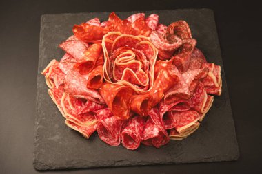 Tahtada farklı et parçaları var. Siyah bir arkaplanda.