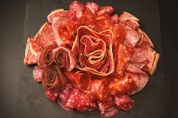 Tahtada farklı et parçaları var. Siyah bir arkaplanda.