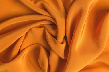 Altın ipek ya da saten lüks kumaş dokusu soyut bir arkaplan olarak kullanılabilir. Üst görünüm.