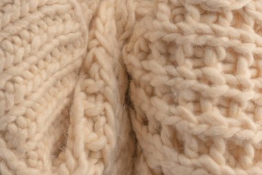 A fragment of beige knitted fabric, knitted from white sheep wool. Knitted background. 