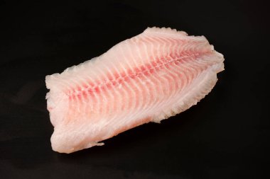 Siyah arkaplanda taze tilapia filetosu, üst görünüm. 