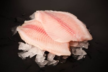 Taze tilapia fileto buzlu, siyah arkaplanda.