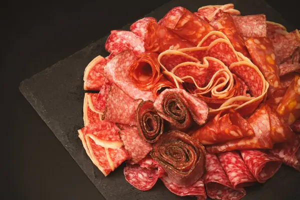 Tahtada farklı et parçaları var. Siyah bir arkaplanda.