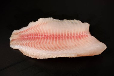 Siyah arkaplanda taze tilapia filetosu, üst görünüm. 
