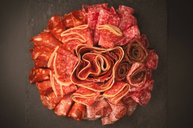 Tahtada farklı et parçaları var. Siyah bir arkaplanda.