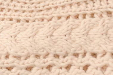 A fragment of beige knitted fabric, knitted from white sheep wool. Knitted background. 