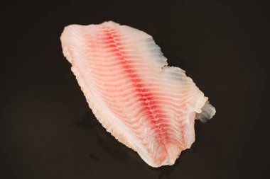 Siyah arkaplanda taze tilapia filetosu, üst görünüm. 