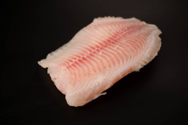 Siyah arkaplanda taze tilapia filetosu, üst görünüm. 
