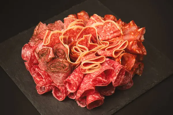 Tahtada farklı et parçaları var. Siyah bir arkaplanda.