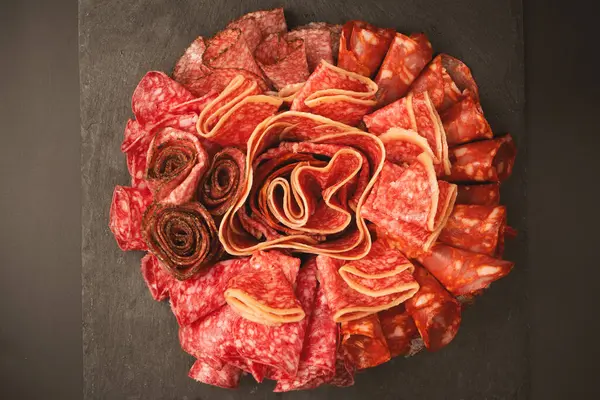 Tahtada farklı et parçaları var. Siyah bir arkaplanda.