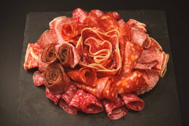 Tahtada farklı et parçaları var. Siyah bir arkaplanda.