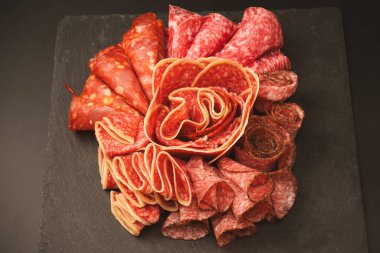 Tahtada farklı et parçaları var. Siyah bir arkaplanda.