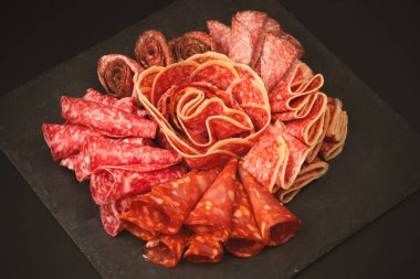 Tahtada farklı et parçaları var. Siyah bir arkaplanda.