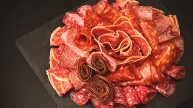 Tahtada farklı et parçaları var. Siyah bir arkaplanda.