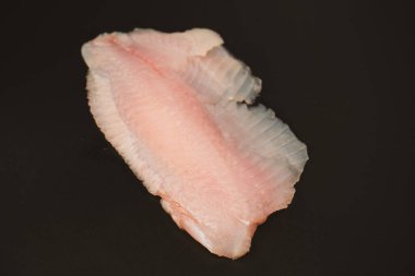 Siyah arkaplanda taze tilapia filetosu, üst görünüm. 
