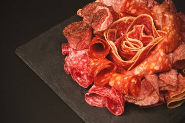 Tahtada farklı et parçaları var. Siyah bir arkaplanda.