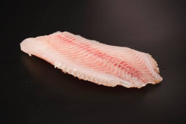 Siyah arkaplanda taze tilapia filetosu, üst görünüm. 