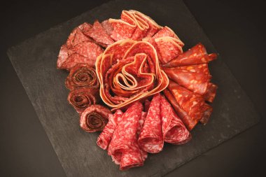 Tahtada farklı et parçaları var. Siyah bir arkaplanda.