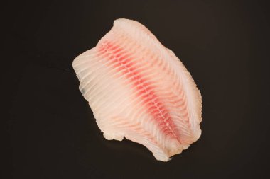 Siyah arkaplanda taze tilapia filetosu, üst görünüm. 