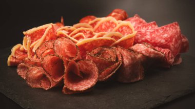 Tahtada farklı et parçaları var. Siyah bir arkaplanda.