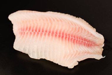 Siyah arkaplanda taze tilapia filetosu, üst görünüm. 