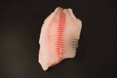 Siyah arkaplanda taze tilapia filetosu, üst görünüm. 
