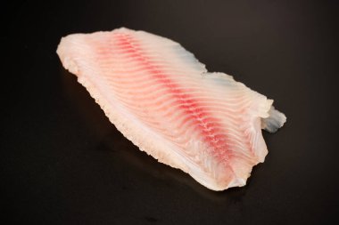 Siyah arkaplanda taze tilapia filetosu, üst görünüm. 