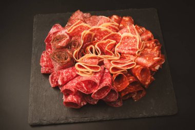 Tahtada farklı et parçaları var. Siyah bir arkaplanda.